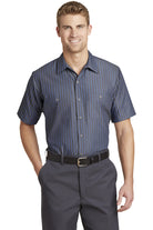 Male model wearing Red Kap Men's Short Sleeve Striped Industrial Work Shirt in gray with blue vertical stripes, featuring button-front closure and dual chest pockets.