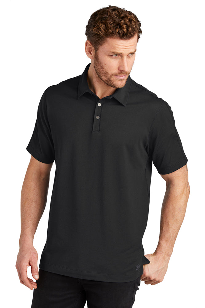 Male model in OGIO Onyx Polo in blacktop color, featuring moisture-wicking performance fabric and sleek three-button placket.