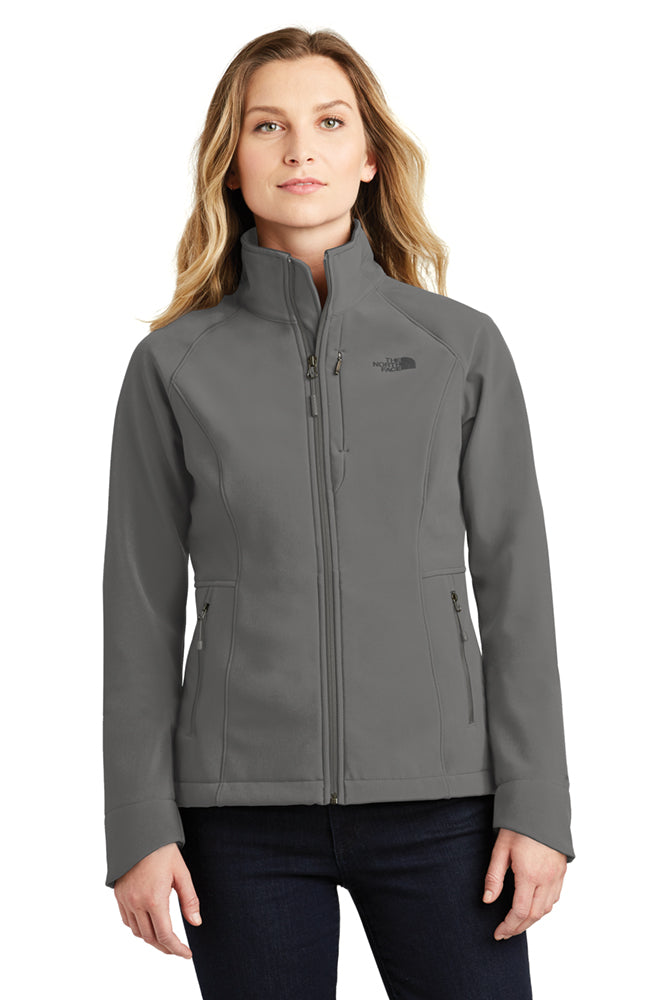 Female model wearing The North Face Ladies Apex Barrier Soft Shell Jacket in asphalt grey, showcasing the tailored silhouette, full front zip, and logo detail.