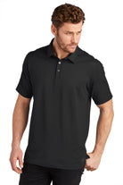  Male model in OGIO Onyx Polo in blacktop color, featuring moisture-wicking performance fabric and sleek three-button placket.