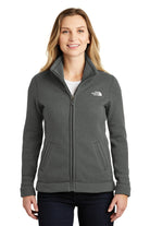  Woman wearing The North Face Ladies Sweater Fleece Jacket in black heather, showing full-zip front, high collar, and tailored fit with logo on left chest.